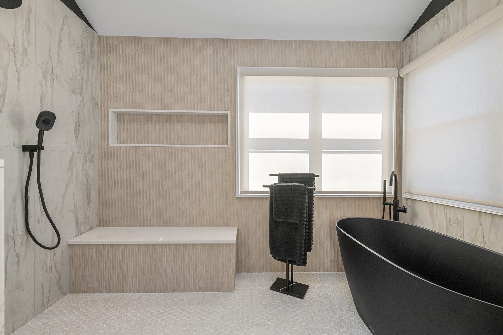 Marble shower with black fixtures and a freestanding tub